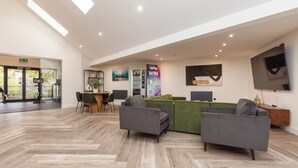 A spacious lobby with a herringbone floor pattern, a reception desk, and seating areas. - Riverside House by UTDM (Salford)