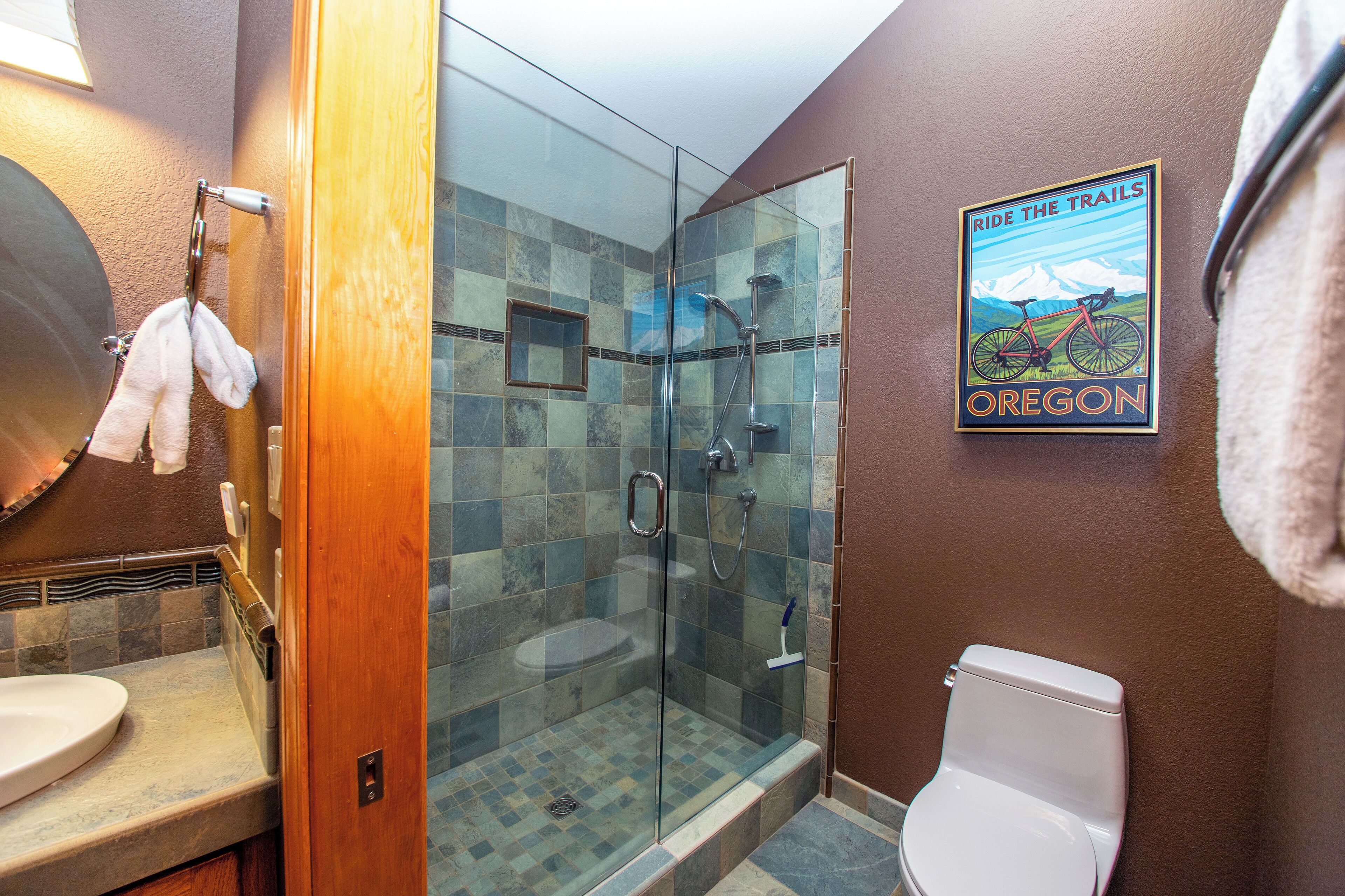 A bathroom with a glass shower enclosure, a toilet, and a sink.