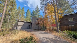 A two-story building with a garage, surrounded by trees and a wooden fence.