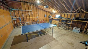 Une pièce spacieuse équipée d’une table de ping-pong, de vélos et dotée d’un décor intérieur en bois.
