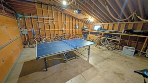 A spacious room with a ping pong table, bicycles, and a wooden interior.