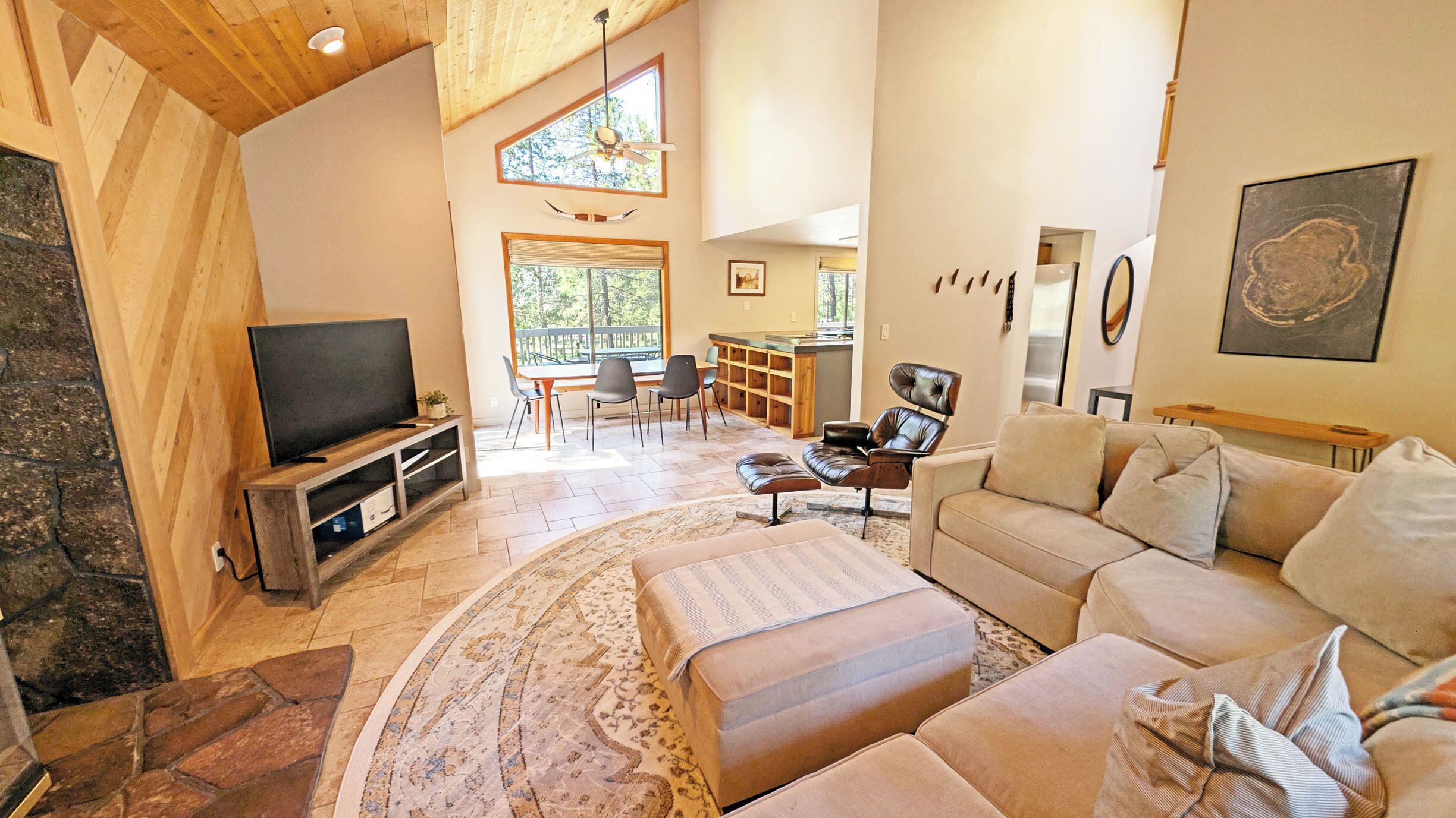 A spacious living room with a large TV, comfortable seating, a dining area, and a kitchen.