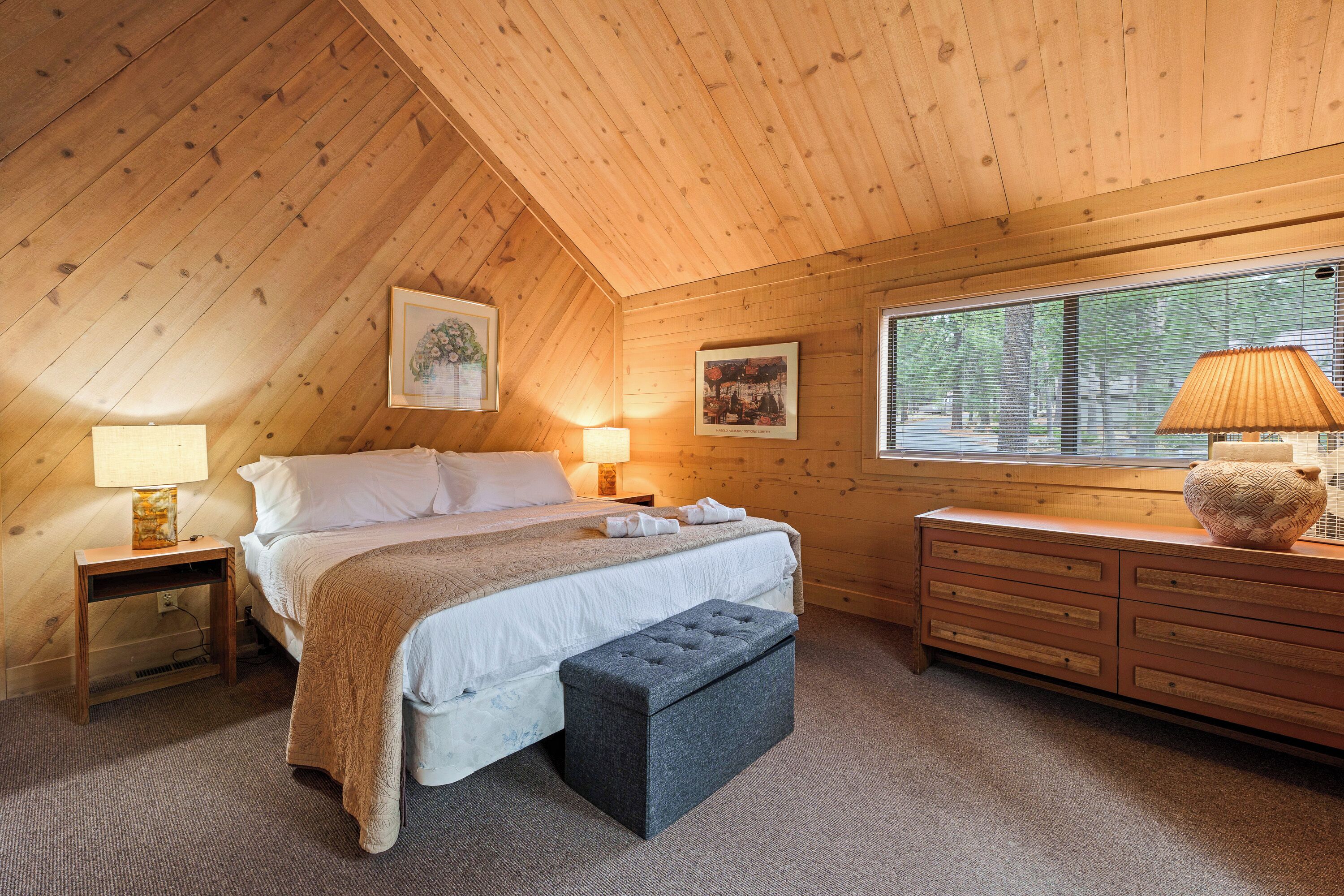 Un dormitorio acogedor con cama, mesitas de noche, cómoda y ventana con persianas.
