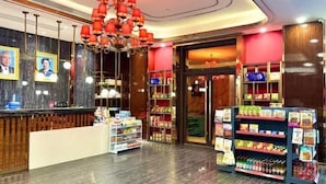 A hotel lobby with a reception desk, a chandelier, and shelves stocked with snacks and beverages. - Meihao Hotel (Sihanoukville)