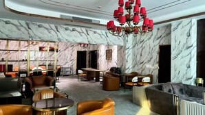 A modern lobby with marble walls, leather seating, and a chandelier. - Meihao Hotel (Sihanoukville)