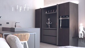 Une cuisine moderne avec des meubles de couleur sombre, un four encastré et une sculpture décorative.