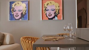 Un coin repas avec une table dressée pour quatre personnes, deux œuvres d’art encadrées accrochées au mur et une chaise en osier.