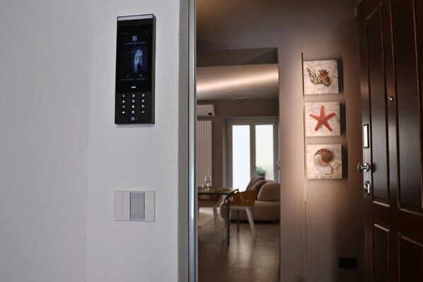 Un couloir doté d’une serrure électronique, un coin repas avec des chaises et une table, et des œuvres d’art accrochées au mur.