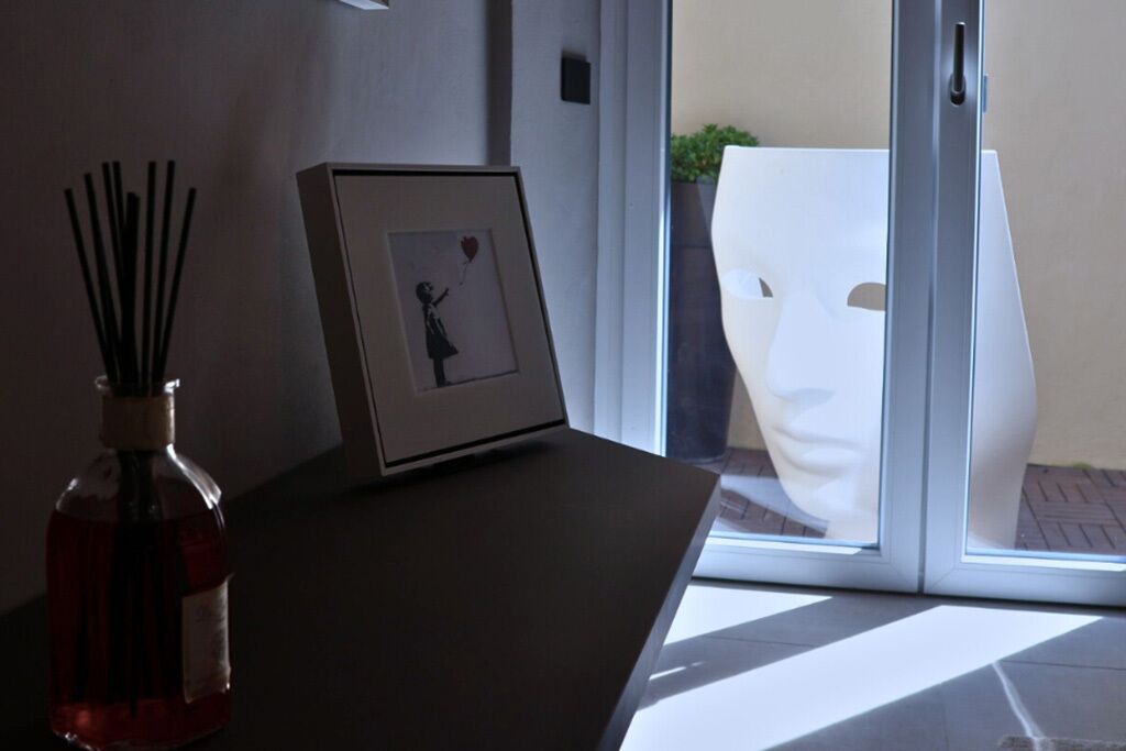 Une pièce avec une porte vitrée donnant sur l’extérieur, un tableau encadré posé sur une table et une bouteille contenant un liquide.