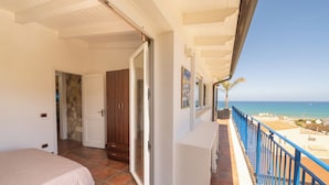 Une chambre avec un lit, une salle de bain et un balcon donnant sur la mer.