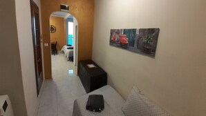 Un couloir avec un lit, une petite table et un tableau accroché au mur.