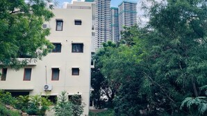 Un edificio de varios pisos con fachada plana, rodeado de abundante vegetación.