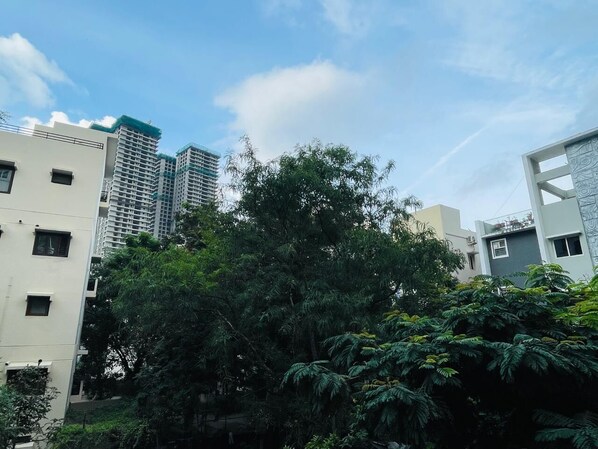 A high-rise building with multiple floors, surrounded by dense greenery and other residential buildings. - Zivo Stays, Jubilee Hills (Hyderabad)