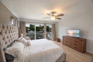Ein Schlafzimmer mit einem großen Bett, einem Deckenventilator, einer Holzkommode und einem Fernseher.