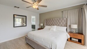 A bedroom with a large bed, a ceiling fan, a nightstand with a lamp, and a mirror on the wall. - Intracostal Beauty in Fort Lauderdale (Fort Lauderdale)