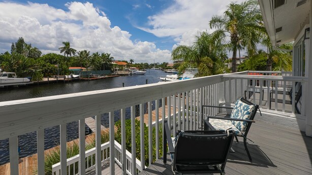 A deck with outdoor seating overlooking a marina with boats and palm trees. - Waterside Retreat in Fort Lauderdale (Fort Lauderdale)