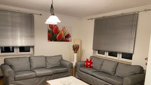 Een woonkamer met twee grijze banken, een witte salontafel en zwarte stoelen.