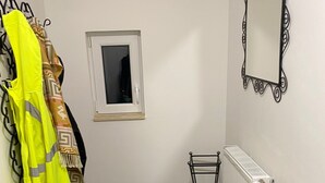 Een kleine, smalle badkamer met een radiator, een spiegel en een droogrek.