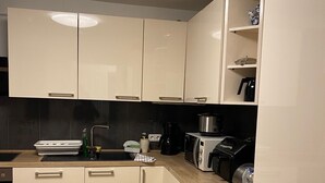 Een moderne keuken met witte kastjes, een houten aanrechtblad en een zwarte achterwand.