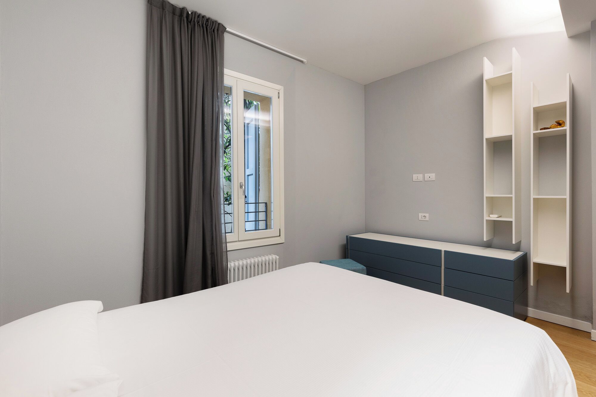 Un dormitorio con cama, cómoda, armario y ventana con cortinas.