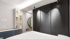 Une chambre à coucher moderne, comprenant un lit, une armoire intégrée, un miroir et une étagère.