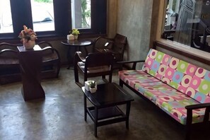 A seating area with a sofa, chairs, a small table, and a vase with flowers. - Hug Fang Hotel (Fang)