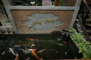 A koi pond with a brick wall and the name 'Jiu Fang' in gold letters.