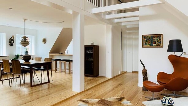 Un amplio salón con techo alto, una mesa de comedor y mobiliario moderno.