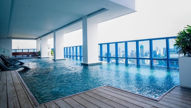 Une piscine intérieure moderne avec vue sur la ville, une terrasse en bois et un espace détente.