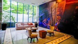 Un hall d’hôtel moderne avec une grande fenêtre, un canapé, une table basse et un fauteuil.