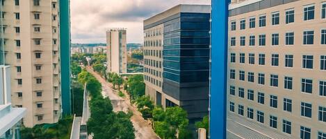 A modern urban street with high-rise buildings, a clear road, and green trees.