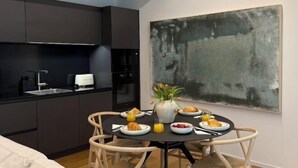 A compact kitchen with dark cabinets, a dining table with chairs, and a large abstract painting on the wall. - The Golden loft by Aura Luxury Collection (Como)