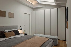 A modern bedroom with a skylight, a bed with pillows, a bedside table with a lamp, and a wardrobe. - The Golden loft by Aura Luxury Collection (Como)