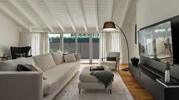 A modern living room with a sofa, ottoman, and a TV on a black stand. - The Golden loft by Aura Luxury Collection (Como)