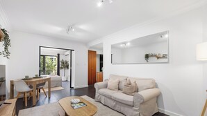A modern living room with a sofa, coffee table, and dining area. - CBD Edge 1BR on Mounts Bay Road (Perth)