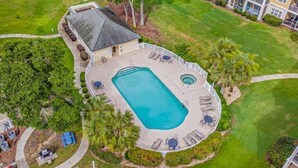 Vista aérea de una propiedad residencial con piscina, muebles de jardín y césped cuidado.