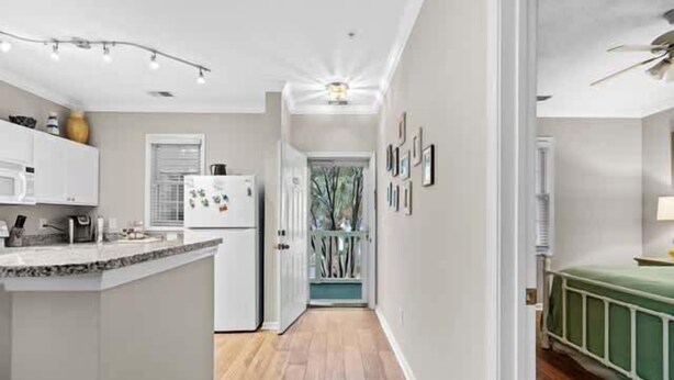 Una cocina moderna con una isla central, armarios blancos y piso de madera.