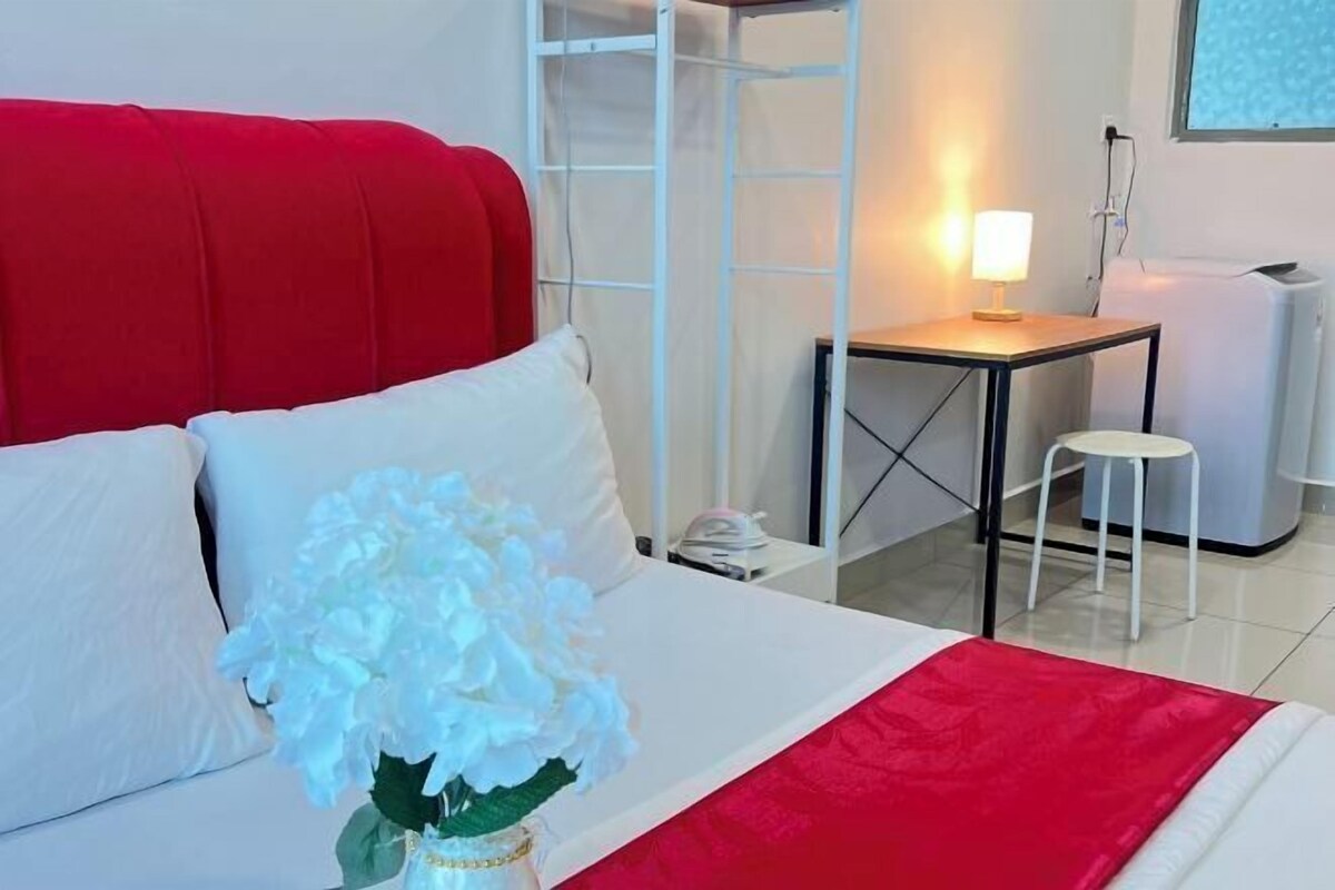 A hotel room with a bed, a bedside table with a lamp, a chair, and a white radiator.