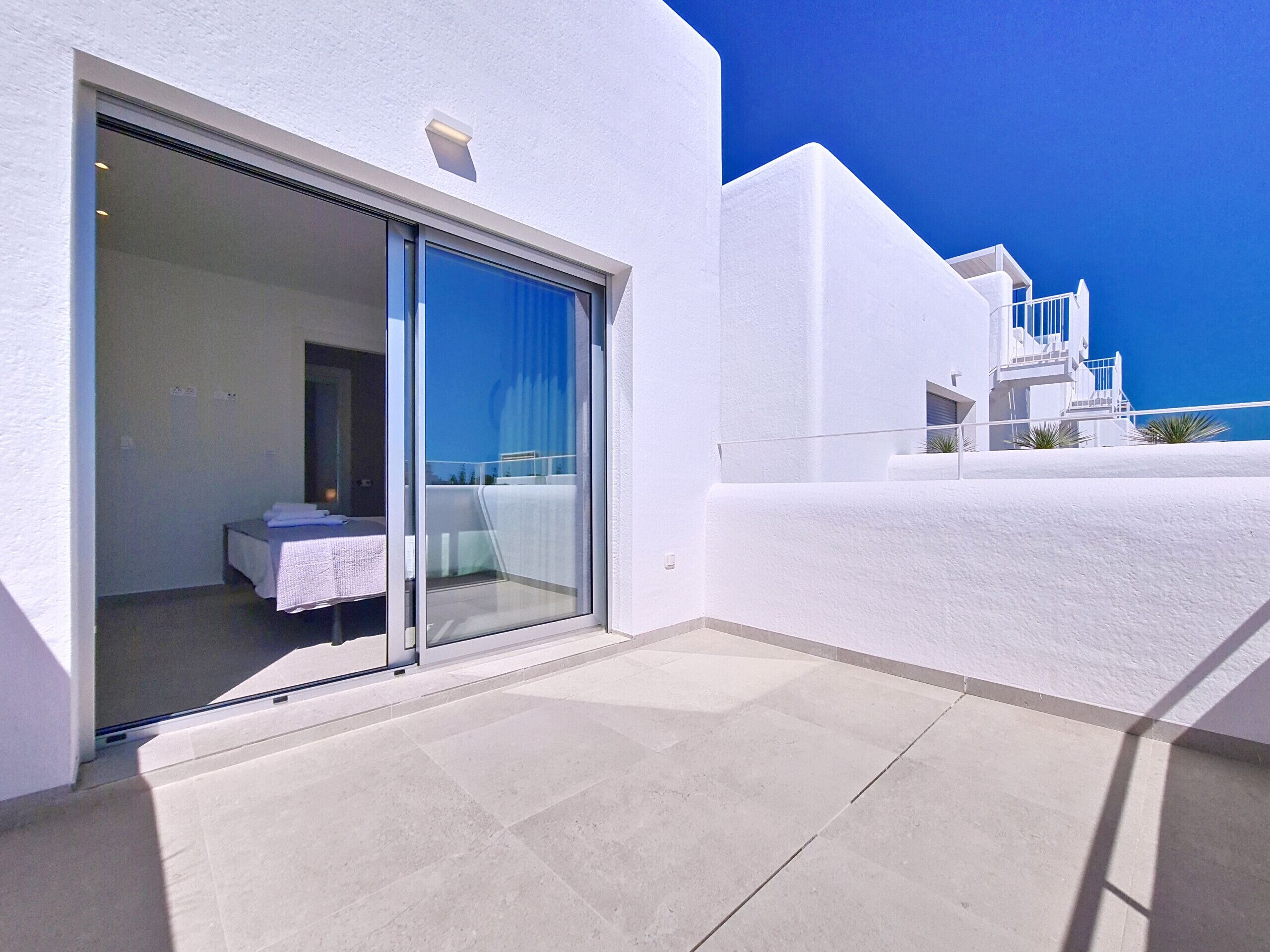 A modern hotel room with a sliding glass door leading to a balcony.