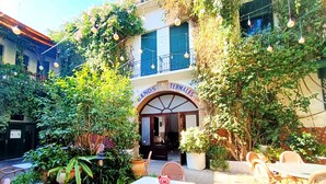 An outdoor seating area with wicker furniture and potted plants, a building entrance with a sign reading "TERMALES", and string lights hanging above. - Villa with private pool, BBQ and large patio (Los Alcazares)
