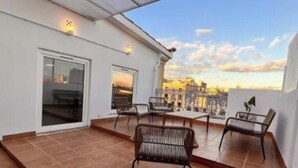 Une terrasse sur le toit, dotée d’un sol carrelé, de deux espaces de détente avec des chaises, et offrant une vue sur le paysage urbain.