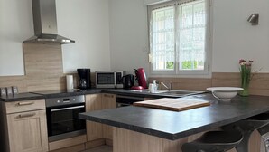 Una cucina moderna con isola centrale, elettrodomestici in acciaio inossidabile e un'ampia finestra con tende in pizzo.