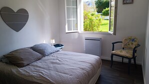 Una camera da letto con un letto, una sedia, una finestra e un termosifone.