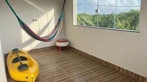 Ein Zimmer mit einer Hängematte, einem kleinen Hocker und einem gelben Kajak.