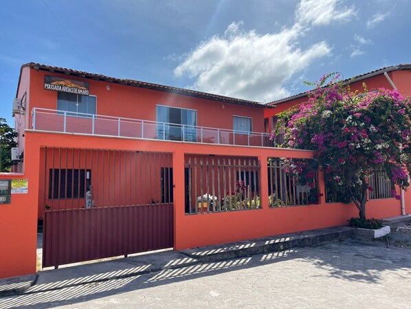 A two-story building with a red facade, a gated entrance, and a balcony.