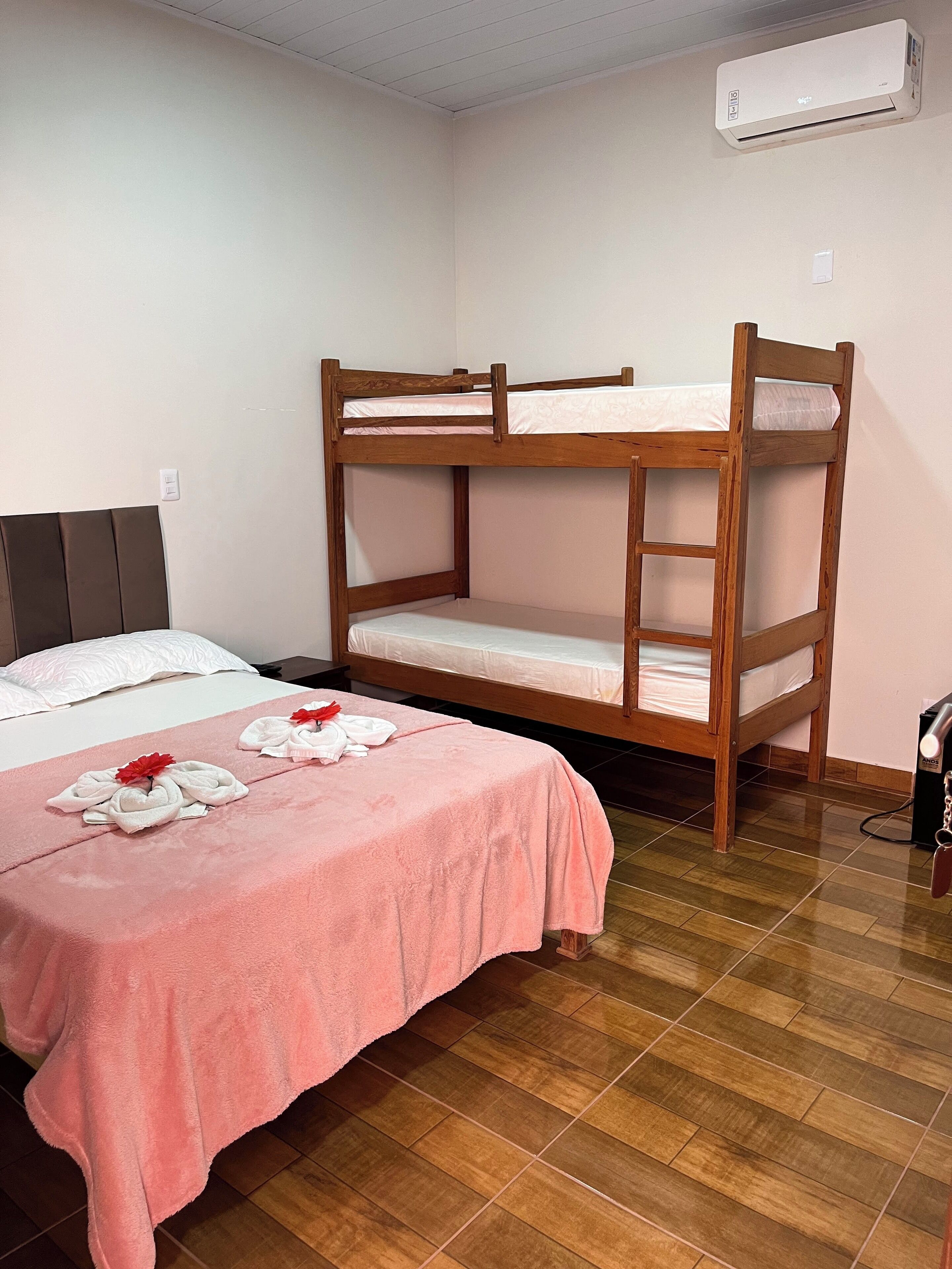 Dormitorio con literas, colcha rosa, almohada blanca y decoración con una flor roja.