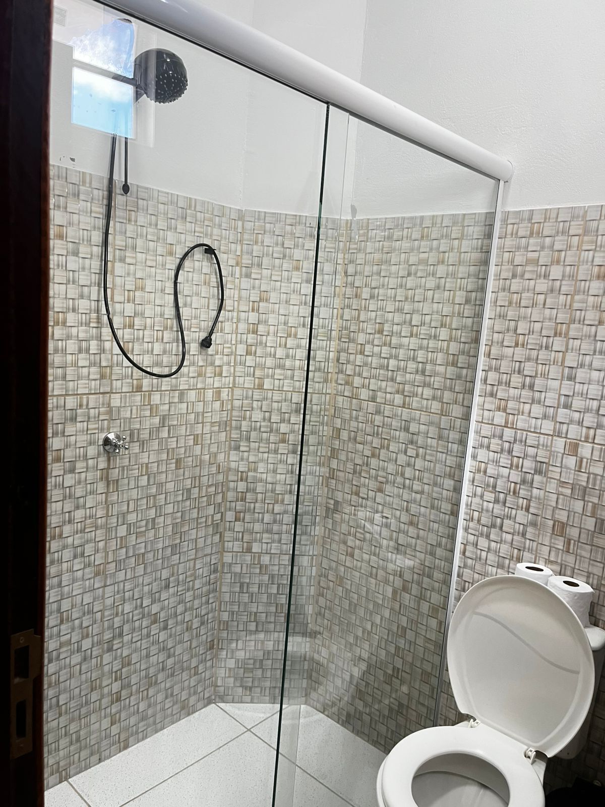 A bathroom with a shower, toilet, and tiled walls.