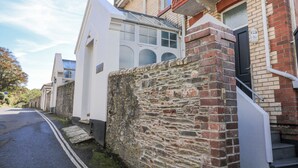 A narrow street with a stone wall and a white building with a black door. - Fastnet at Nonsuch House (Dartmouth)