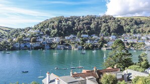 A coastal town with houses along the water, boats, and a hill in the background. - Fastnet at Nonsuch House (Dartmouth)