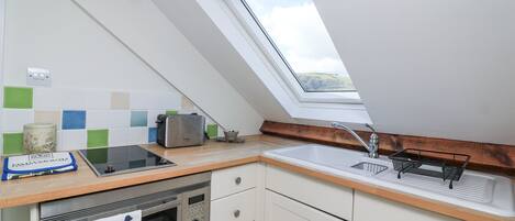 A kitchen with a skylight, a microwave, a toaster, and a sink.
